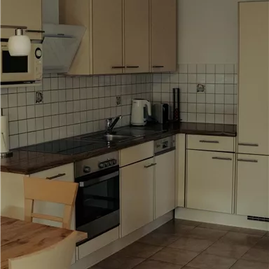 A modern kitchen with bright cabinets and a wooden countertop. It is well equipped with appliances such as a stove and a microwave.