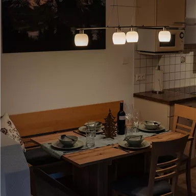 A modern dining room with a wooden table and elegant chairs. Stylish lamps hang above the table in a cozy space.