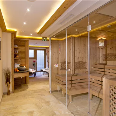 Ein moderner Saunabereich aus Holz mit sanftem Licht. Der Raum ist minimalistisch und einladend gestaltet, mit großen Glaswänden und gemütlicher Atmosphäre.