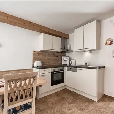 A modern kitchen unit with bright cabinets and a wooden dining table. The atmosphere is cozy and inviting.