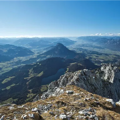 An impressive view of a mountain landscape with green valleys and a blue sky. The rocks in the foreground complement the idyllic backdrop.