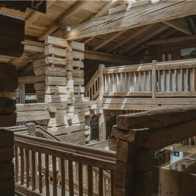 A rustic wooden structure with multiple levels and railings. Light filters through the windows, creating a warm atmosphere.