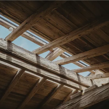 A bright wooden roof structure with window openings. The view shows the clear sky above.