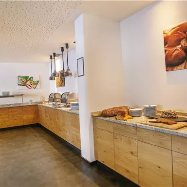 A bright buffet restaurant with wooden shelves. Fresh fruit and bread are arranged on the table.