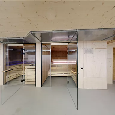 A modern wellness area with glass walls and wooden interior. The room includes two saunas and a relaxing atmosphere.