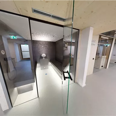 A modern room with glass walls and a minimalist design. The room is bright and open, with a touch of elegance.