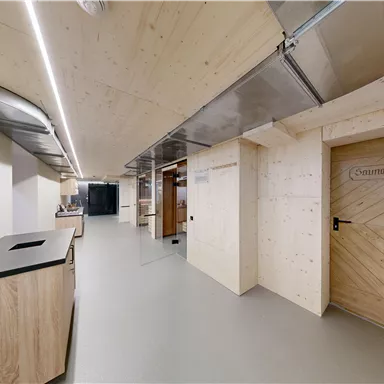 A modern interior with wooden paneling and a clear, minimalist design. On the right side, there is a door with the label "Sauna area".