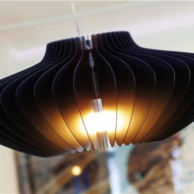 A modern lamp with a curved, layered shape. It emits warm light and gives the room a stylish atmosphere.