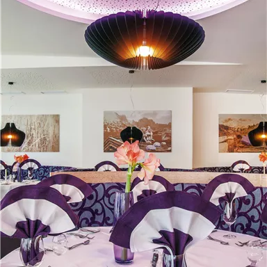 A stylish restaurant with elegant tables and purple decor. The soft lighting creates a cozy atmosphere.