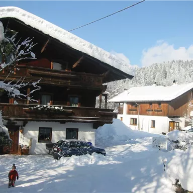 A snow-covered mountain village with traditional wooden houses.
Children are playing in the snow in front of the houses.
