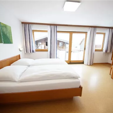 Ein gemütliches Schlafzimmer mit einem großen Bett und einem schönen Ausblick auf die Terrasse. Das Zimmer ist hell und modern eingerichtet, mit einem kleinen Tisch und Blumen auf dem Nachttisch.