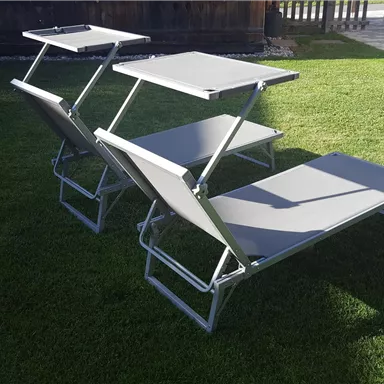 Two adjustable loungers are located on a green meadow. The loungers have a modern gray color and are ideal for relaxing outdoors.