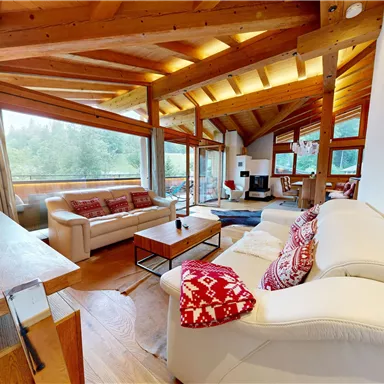 A modern living room with a wooden ceiling and large windows. Natural lighting creates a cozy atmosphere.