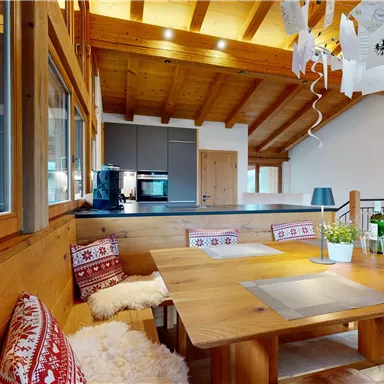 A cozy wooden porch with a large dining table and seating areas. Bright windows let in plenty of light and create an inviting atmosphere.