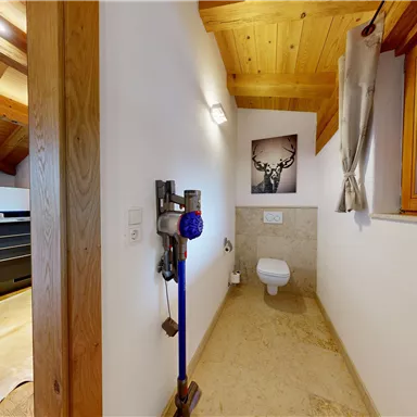 A modern bathroom with a bright wooden ceiling and a large window. In the background, an elegant shower and a decorative painting are visible.