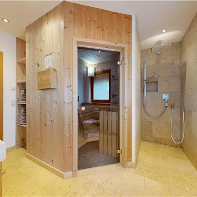 A modern bathroom with wooden details and sauna access. The walls are bright and the furnishings appear inviting and friendly.