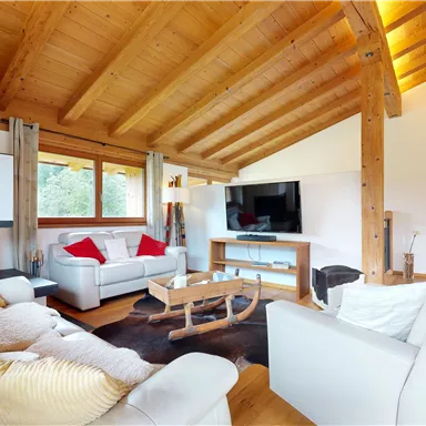A modern living room with wooden ceilings and large windows. The furniture is bright and cozy, perfect for relaxation.