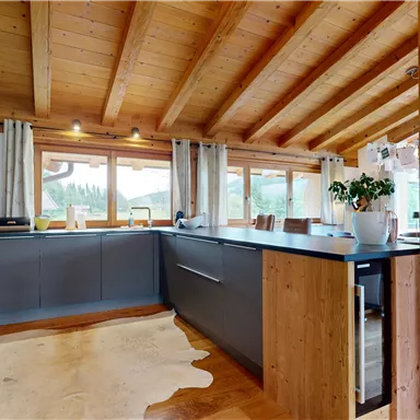 A modern kitchen with wooden details and large windows. The room is bright and inviting, ideal for sociable cooking.