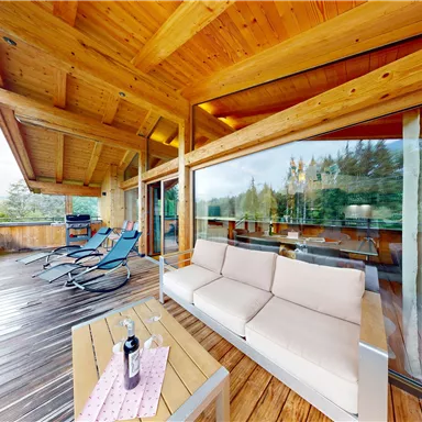 A cozy terrace with wooden paneling and modern furniture. The view of the surrounding nature creates a relaxing atmosphere.