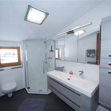 Ein modernes Badezimmer mit einer Dusche, einem spülbaren WC und einem eleganten Waschtisch. Helle Wände und Holzdetails sorgen für eine angenehme Atmosphäre.