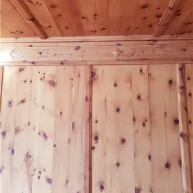 A wooden wall with visible grain and embellishments. The ceiling is also made of wood and has a rustic appearance.