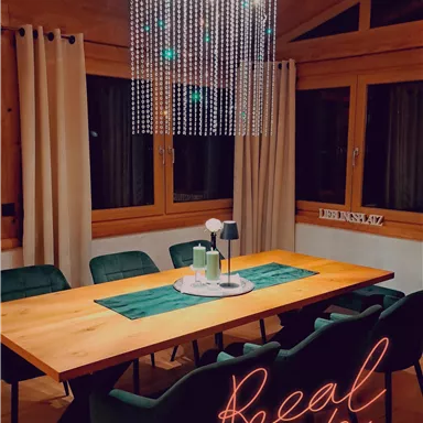 A stylish dining area with a long table and elegant chairs. A modern ceiling lamp provides cozy lighting in the room.