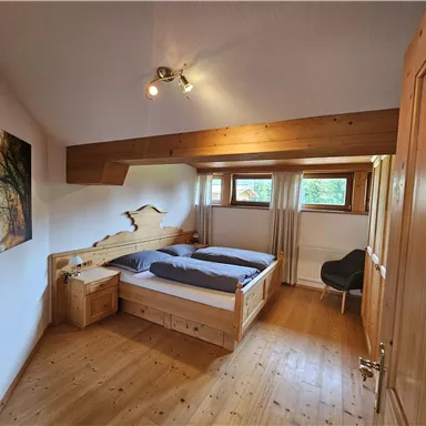 Ein gemütliches Schlafzimmer mit einem Doppelbett und Holzfußboden. Es gibt ein Fenster mit Blick ins Freie und ein Bild an der Wand.