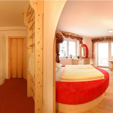 A cozy room with a large bed, a shower, and a bright window. The decor is modern with warm colors and wooden elements.