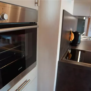 Eine moderne Küche mit einem eleganten Backofen und einem Kochfeld. Die Geräte haben eine glänzende Oberfläche und sind gut angeordnet.