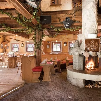Ein gemütliches Restaurant mit Holzdekor und einem großen Kamin. Die Einrichtung ist rustikal und einladend.