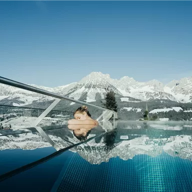 A relaxing pool with a view of snow-covered mountains. The sky-blue reflection of the water enhances the tranquil atmosphere.