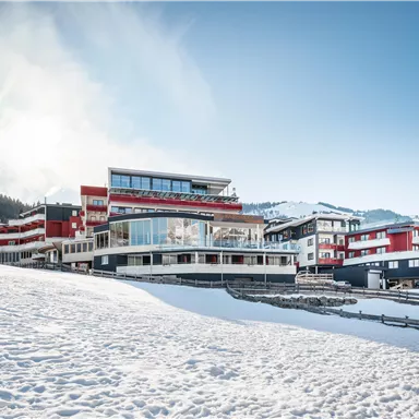 A modern building in a snowy landscape. In the background, mountains and a clear sky can be seen.
