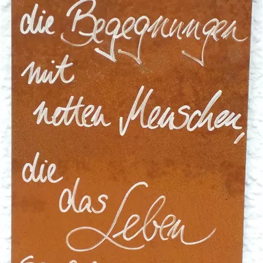 Ein rostiger Schild mit handgeschriebenem Text. Der Spruch beschreibt die Bedeutung von Begegnungen mit netten Menschen im Leben.
