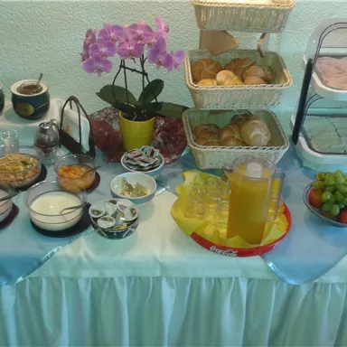 Ein reichhaltiges Frühstücksbuffet mit verschiedenen Speisen und Getränken. Es sind Brötchen, Früchte, Marmelade und Joghurt zu sehen, begleitet von einer schönen Orchidee.