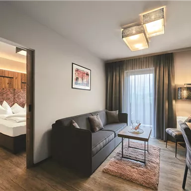 Ein modernes Zimmer mit einem gemütlichen Wohnzimmer und einem Schlafzimmer. Große Fenster sorgen für viel Tageslicht und eine einladende Atmosphäre.