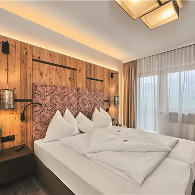 Ein modernes Schlafzimmer mit Holzverkleidung und einem gemütlichen Bett. Große Fenster sorgen für viel natürliches Licht.