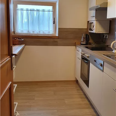 Eine moderne Küche mit hellen Möbeln und Holzdetails. Das Fenster sorgt für viel Tageslicht.