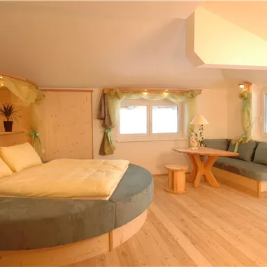 A cozy room with a round bed and a seating area. Warm light and natural materials create an inviting atmosphere.