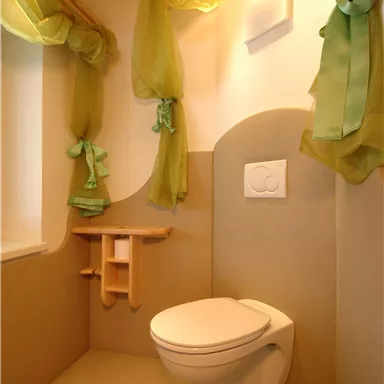A modern toilet with a minimalist design. The walls are in neutral tones, and green curtains add a fresh touch to the room.
