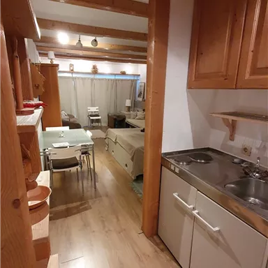 A cozy kitchen with wooden furniture and modern amenities. The view shows a dining area in the background.