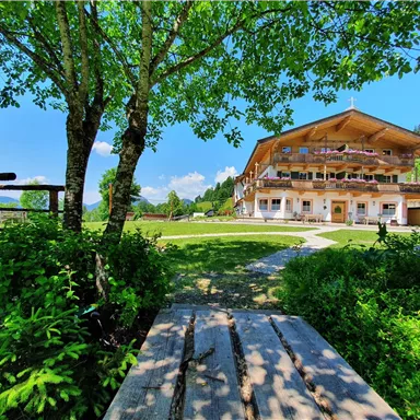 Ein hübsches Gebäude umgeben von grünem Rasen und Bäumen. Der Himmel ist klar und blau, ideal für einen entspannten Aufenthalt.