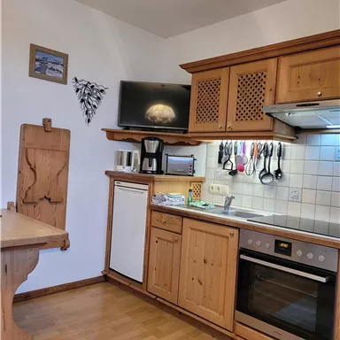 Eine gemütliche Küche mit Holzschränken und modernen Geräten. Ein Esstisch ergänzt den Raum, der gut beleuchtet ist.