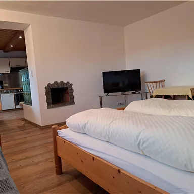 Ein gemütliches Zimmer mit einem Doppelbett, einem Fernseher und einem Esstisch. Die moderne Küche ist gut ausgestattet und sorgt für eine einladende Atmosphäre.