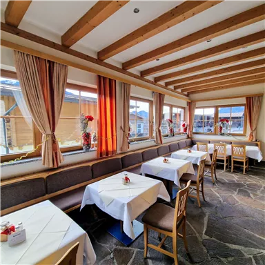 An inviting restaurant with cozy tables and large windows. Bright colors and wooden details create a warm atmosphere.