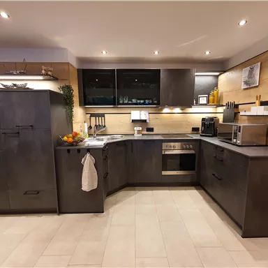 Eine moderne Küche mit dunklen Schränken und Holzdetails. Sie ist gut ausgestattet mit Geräten und hat eine helle, einladende Atmosphäre.