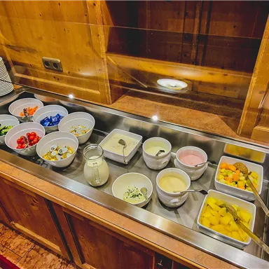 A buffet with a variety of fresh ingredients and sauces. The table is made of wood and provides an inviting atmosphere.