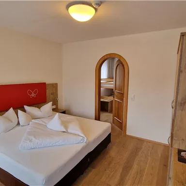 A cozy hotel room with a large bed and white pillows. There is a TV mounted on the wall and there is an attached bathroom.