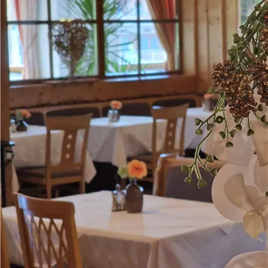A cozy restaurant with set tables and beautiful decoration. Large windows let in a lot of daylight.