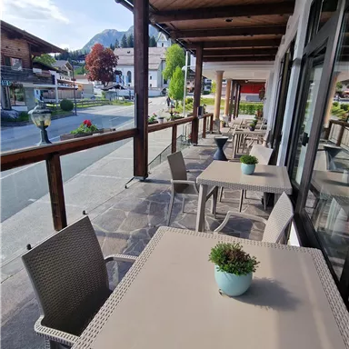 A beautiful outdoor area with tables and chairs. The terrace offers a view of the street and the surrounding landscape.