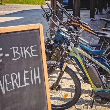 An e-bike rental with several bikes is ready. The sign clearly shows the available e-bikes for renters.